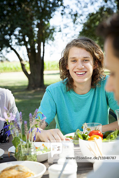 Junger Mann beim Essen mit Freunden im Freien