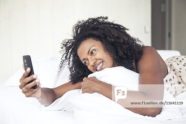 Frau mit Handy im Bett
