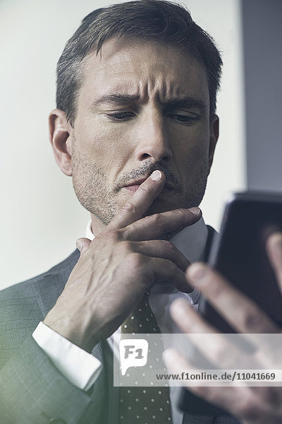 Geschäftsmann betrachtet digitales Tablett mit zerfurchter Stirn