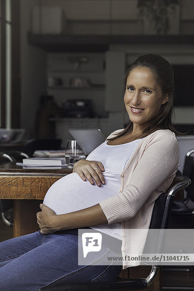 Schwangere Frau wiegt Bauch  Porträt