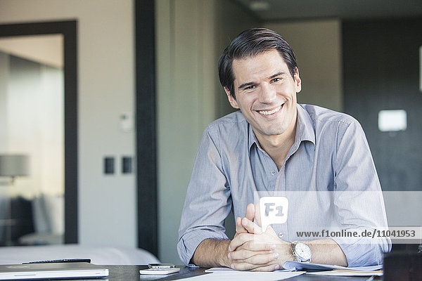 Businessman sitting at desk  smiling  portrait