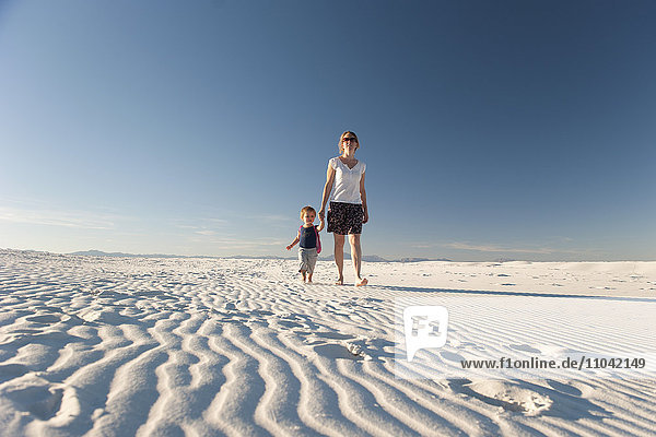 Mother and son walking on dune  White Sands National Monument  New Mexico  USA