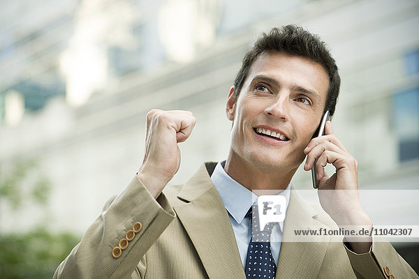 Geschäftsmann feiert gute Nachrichten beim Telefonieren mit dem Handy
