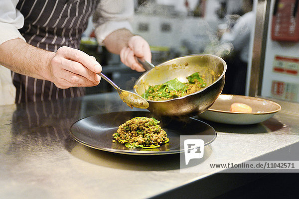 Restaurantkoch stellt gekochtes Linsengericht auf den Teller
