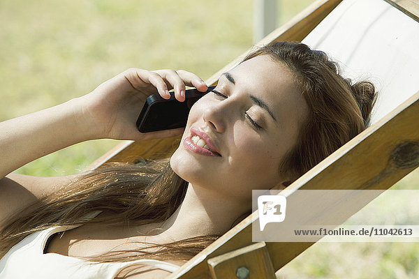 Frau spricht beim Sonnenbaden auf dem Handy