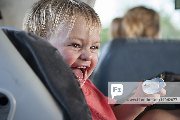 Kleinkind Junge lacht im Auto