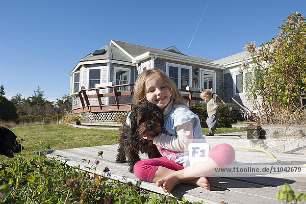 Kleines Mädchen sitzend an Deck mit Haushund