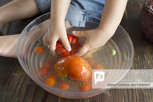 Child washing tomatoes