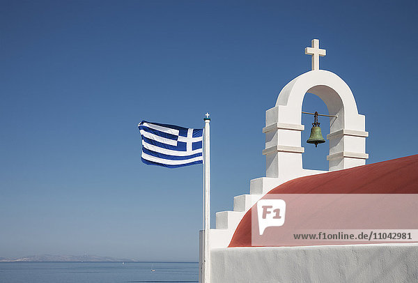 Griechische Flagge und Glockenbogen unter blauem Himmel