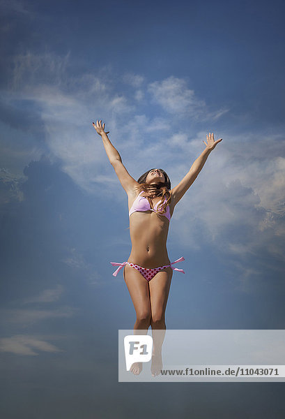 Kaukasische Frau im Bikini springt vor Freude