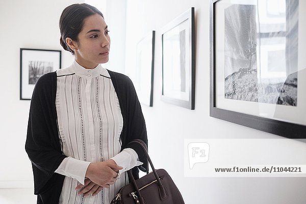 Hispanische Frau bewundert Kunst in einer Galerie