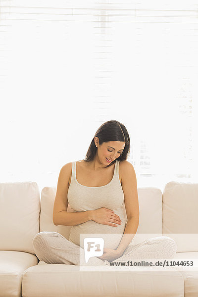 Schwangere kaukasische Frau auf dem Sofa sitzend