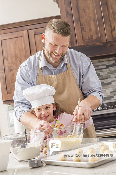 Caucasian father and daughter baking in kitchen