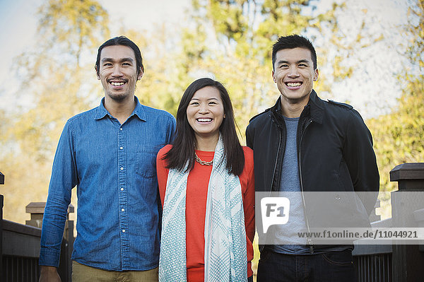 Adult Chinese siblings smiling outdoors
