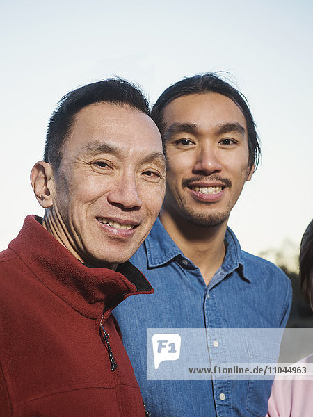 Chinesischer Vater und Sohn lächelnd im Freien