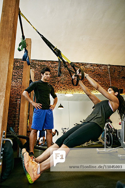 Woman working out with trainer in gymnasium