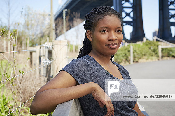 Lächelnde schwarze Frau sitzt auf einer Bank im Freien