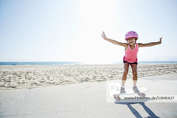Mädchen fährt Skateboard am Strand