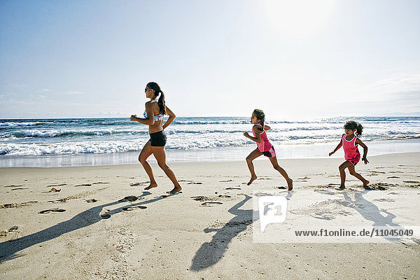 Mutter und Töchter laufen am Strand