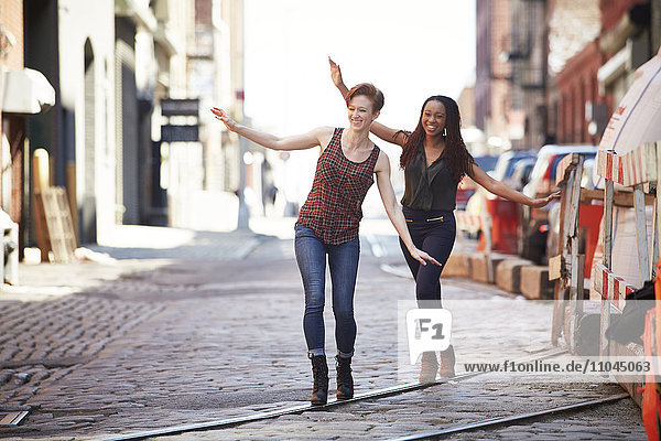Women balancing on track in cobblestone city street