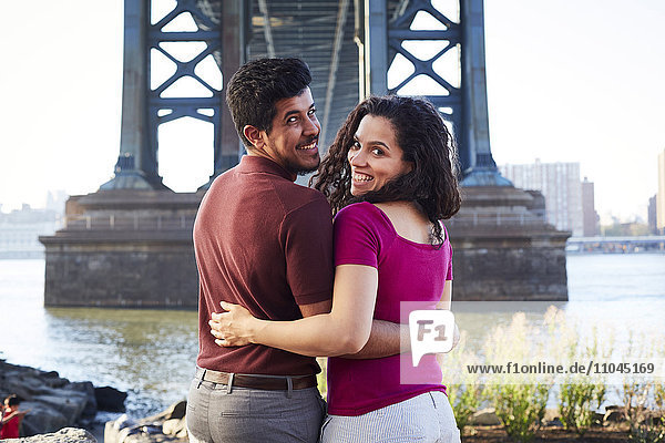 Hugging couple smiling at waterfront