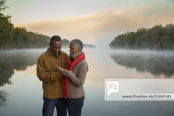 Older couple looking at ring at foggy river at sunrise