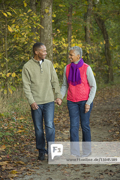 Older couple holding hands walking in forest