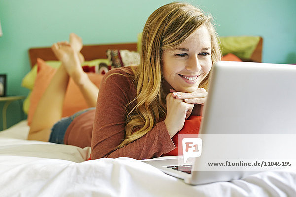 Caucasian woman using laptop on bed