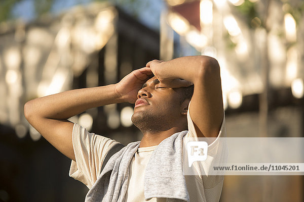 Gemischtrassiger Mann mit Kopfschmerzen im Freien