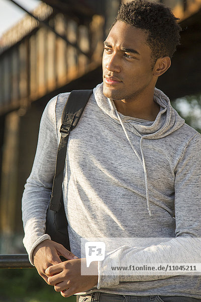 Mixed Race man with shirt draped over shoulders listening to headphones