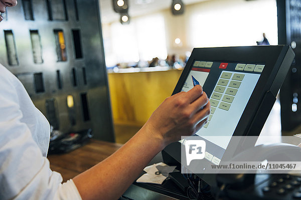 Caucasian cashier using touch screen to process credit card payment