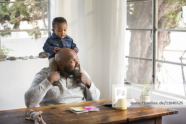 Afroamerikanischer Vater hält seinen kleinen Sohn auf den Schultern