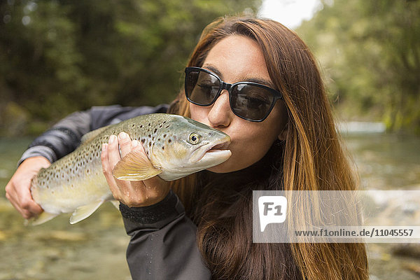 Kaukasische Frau küsst Fisch in abgelegenem Fluss
