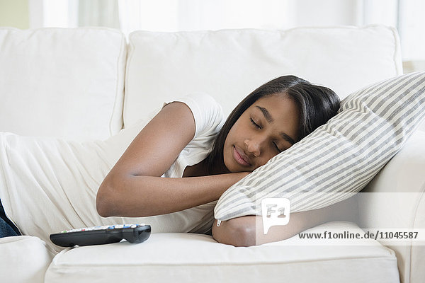 Mixed Race girl sleeping on sofa with pillow