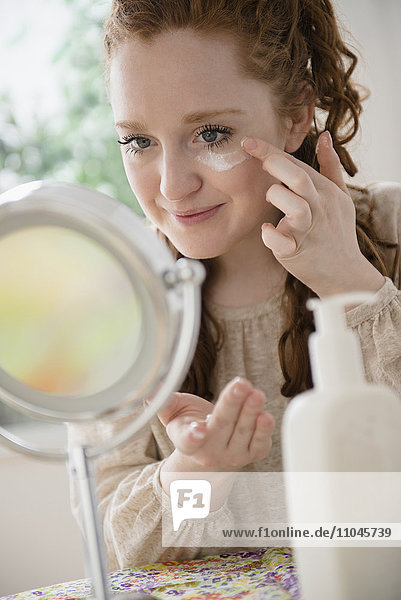 Caucasian woman applying moisturizer to face