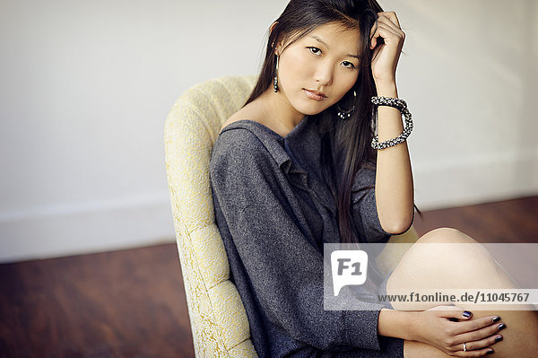 Asiatische Frau im Sessel sitzend