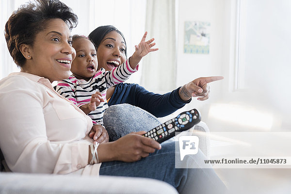 Black multi-generation family watching exciting television