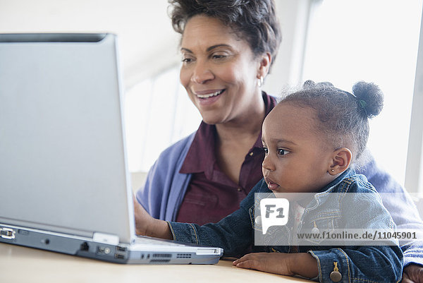 Schwarze Großmutter und Enkelin mit Laptop