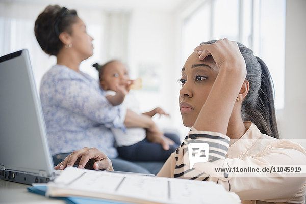 Stressed Black woman paying bills using laptop