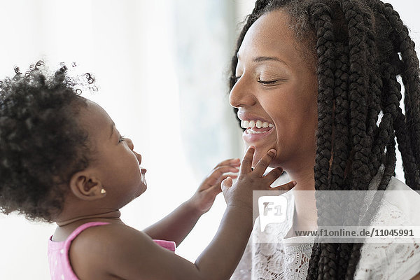 Schwarze Frau spielt mit ihrer kleinen Tochter