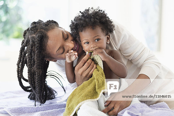 Schwarze Frau trocknet ihre kleine Tochter mit Handtüchern
