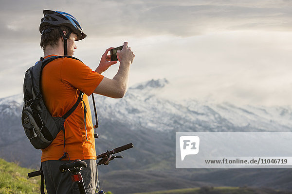 Kaukasischer Mann auf dem Mountainbike beim Fotografieren einer malerischen Aussicht