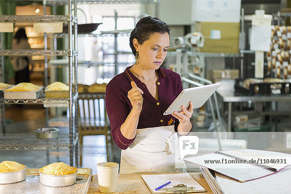 Caucasian woman using digital tablet in bakery
