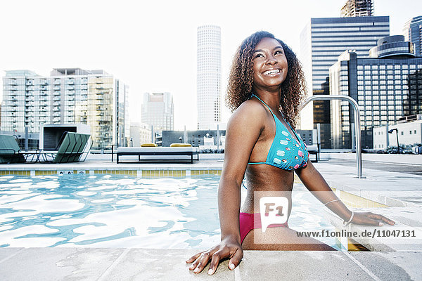 Lächelnde schwarze Frau  die in einem städtischen Schwimmbad steht