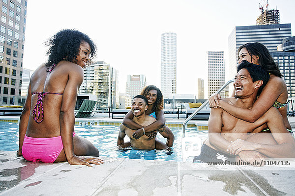 Smiling friends enjoying urban swimming pool