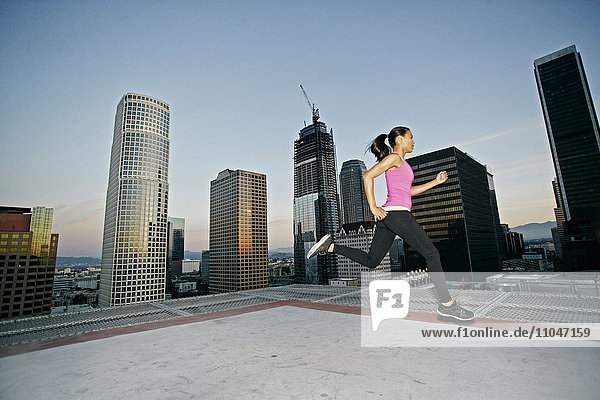 Gemischtrassige Frau läuft auf einem städtischen Hausdach