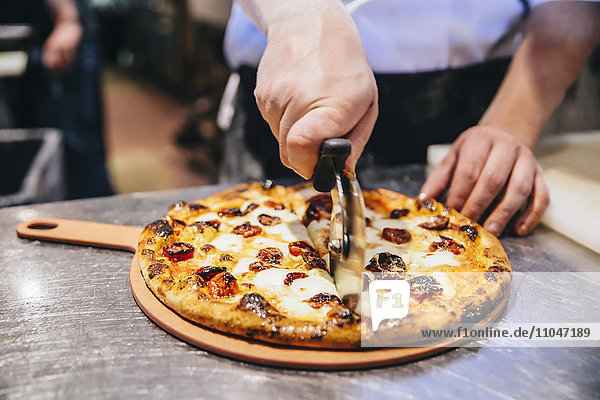 Koch schneidet Pizza in der Restaurantküche