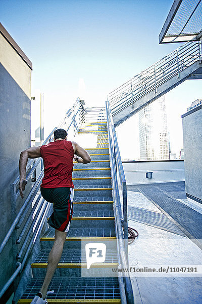 Kaukasischer Mann läuft eine Treppe auf einem städtischen Dach hinauf
