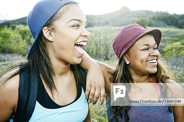 Gemischtrassige Schwestern lachend im Feld