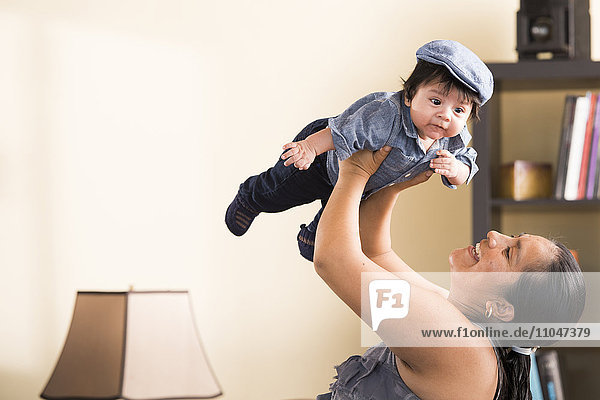 Hispanic woman lifting baby son